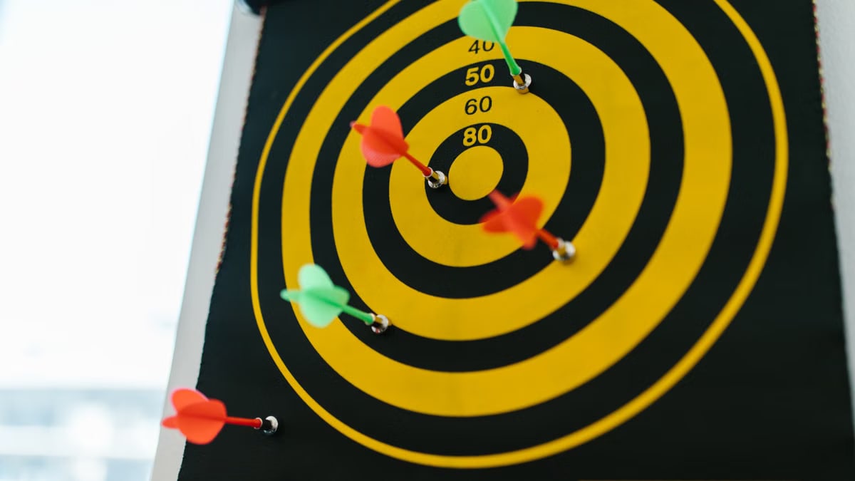 Vibrant darts stuck in a yellow and black dartboard representing precision and strategy.